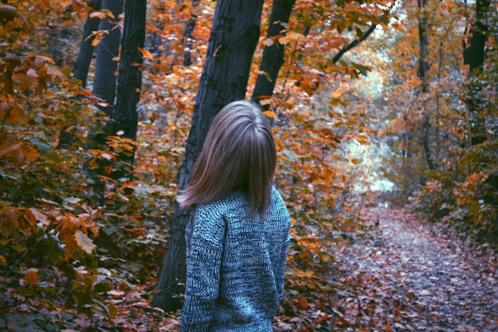 Girl in autumn forest with back