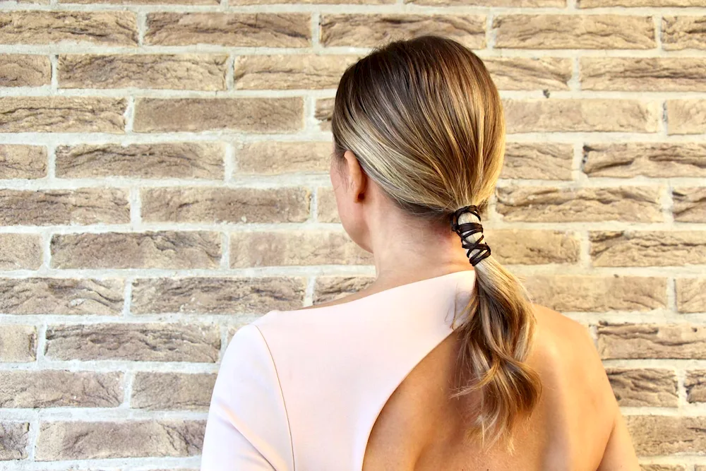 Girl tying her hair in a ponytail