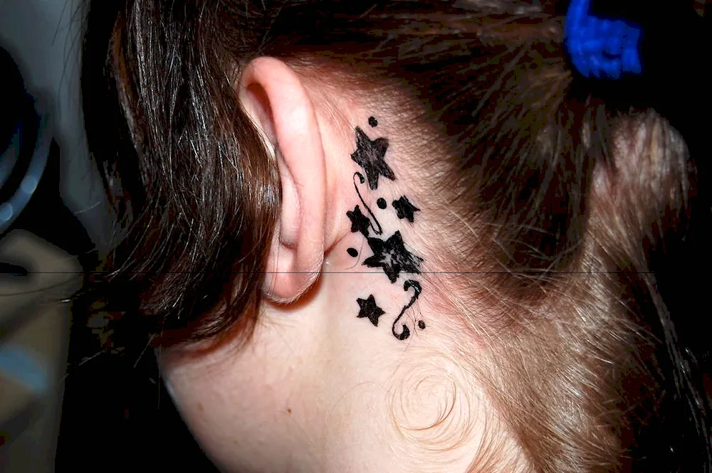 Tattoo of a feather behind the ear